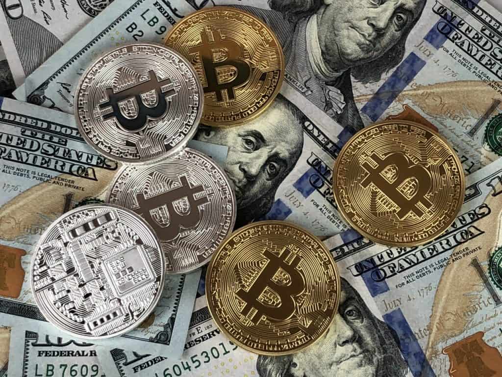 Bitcoin represented as a gold token lying on hundred dollar bills