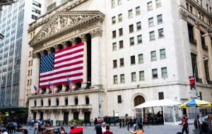 Photo of the NYSE front entrance with US flag draped over the columns